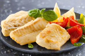 Cooked Atlantic Cod with peppers and lemon wedges